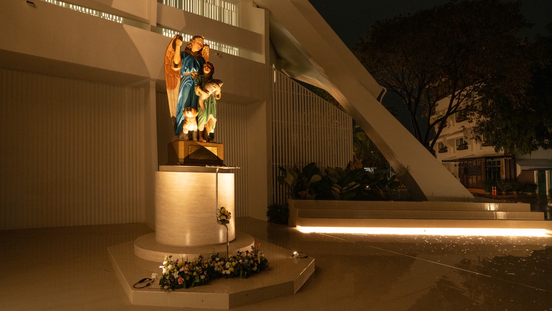 Angel statue at St. Raphael Catholic Church highlighted with warm outdoor lighting