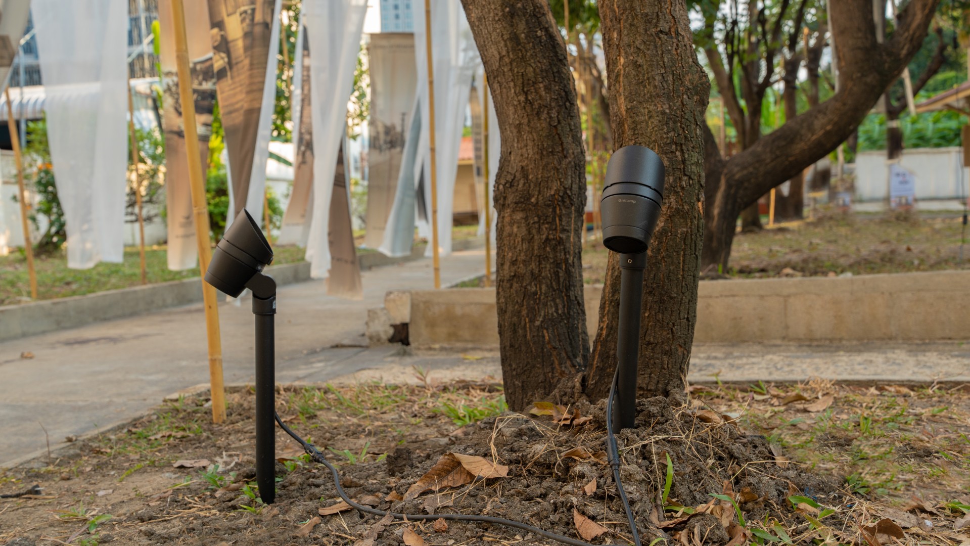 Medium ALPHA Round outdoor spotlights illuminating trees and circulation paths within the exhibition site.