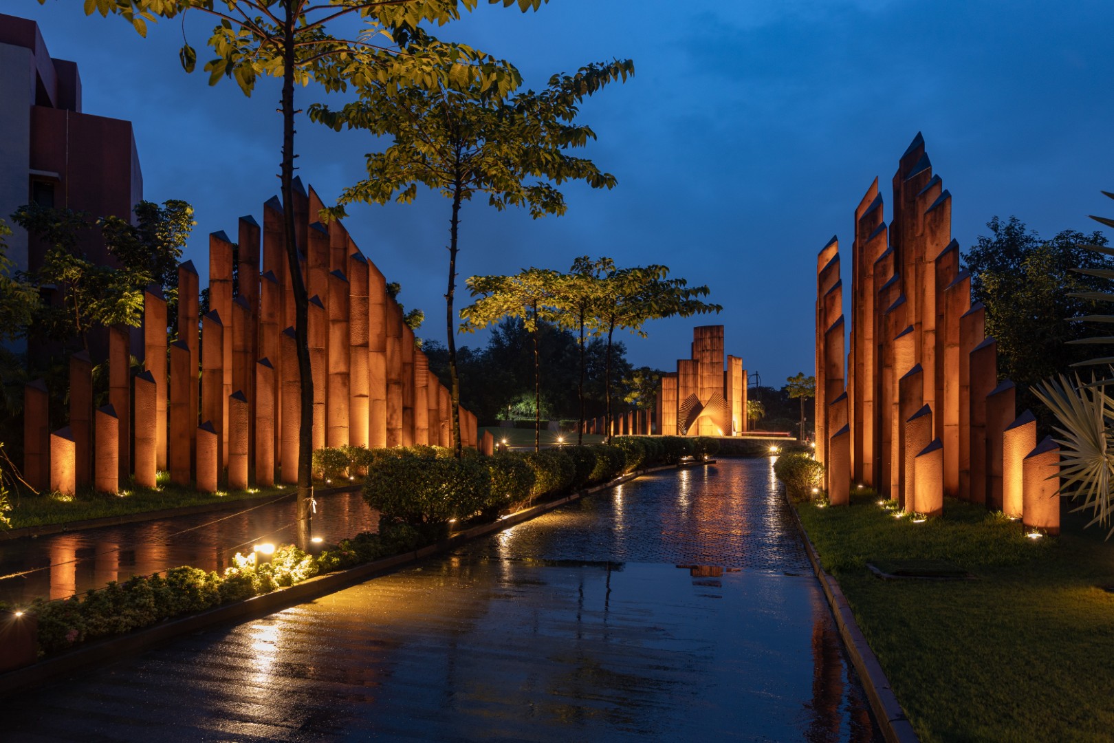 Illuminated sculptural entrance path in modern residential complex at night.