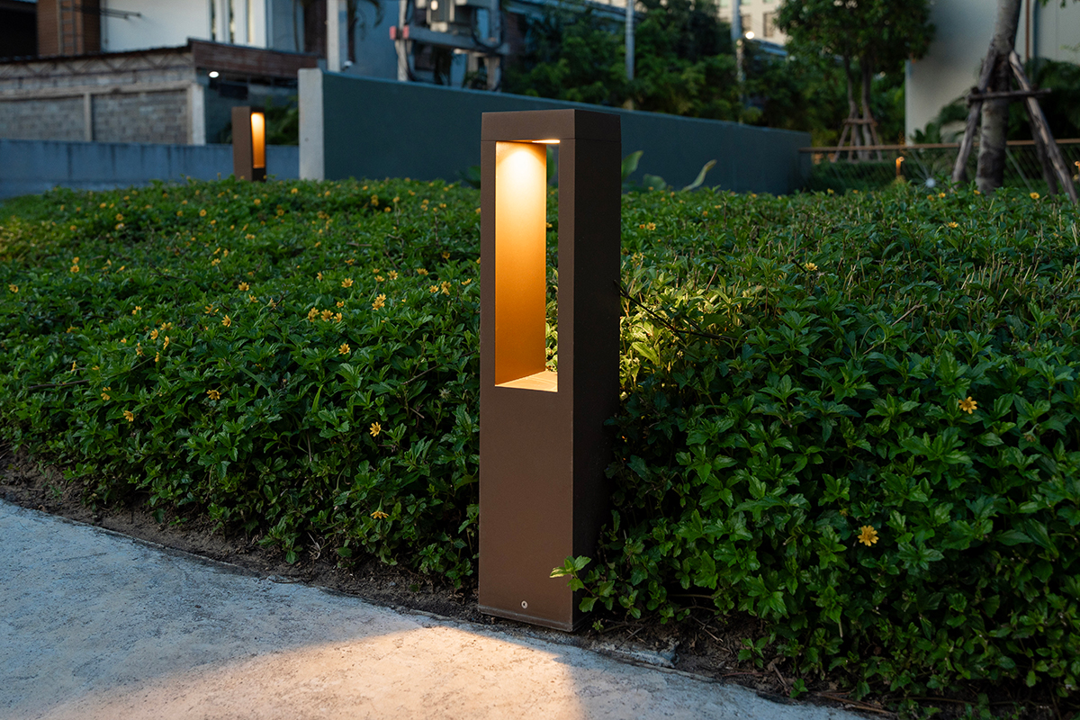 Modern outdoor bollard light illuminating landscaped garden pathway
