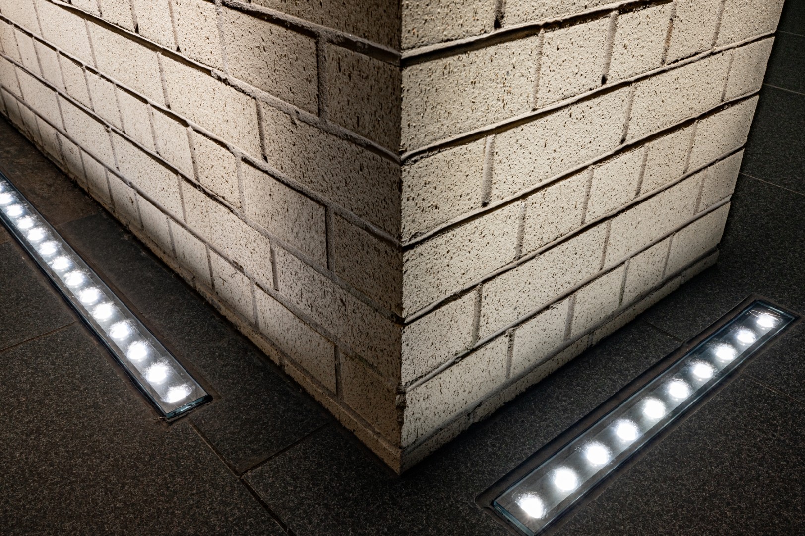 Close-up of brick column illuminated by linear inground LED light