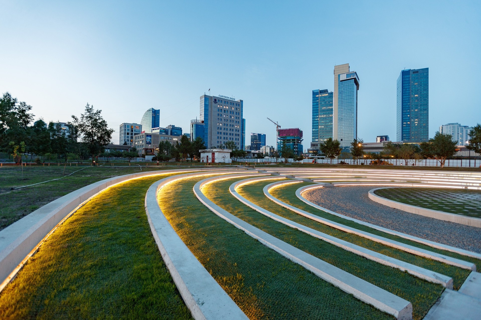 Curved outdoor seating area with linear lighting at National Cultural Recreation Park in Ulaanbaatar during early evening