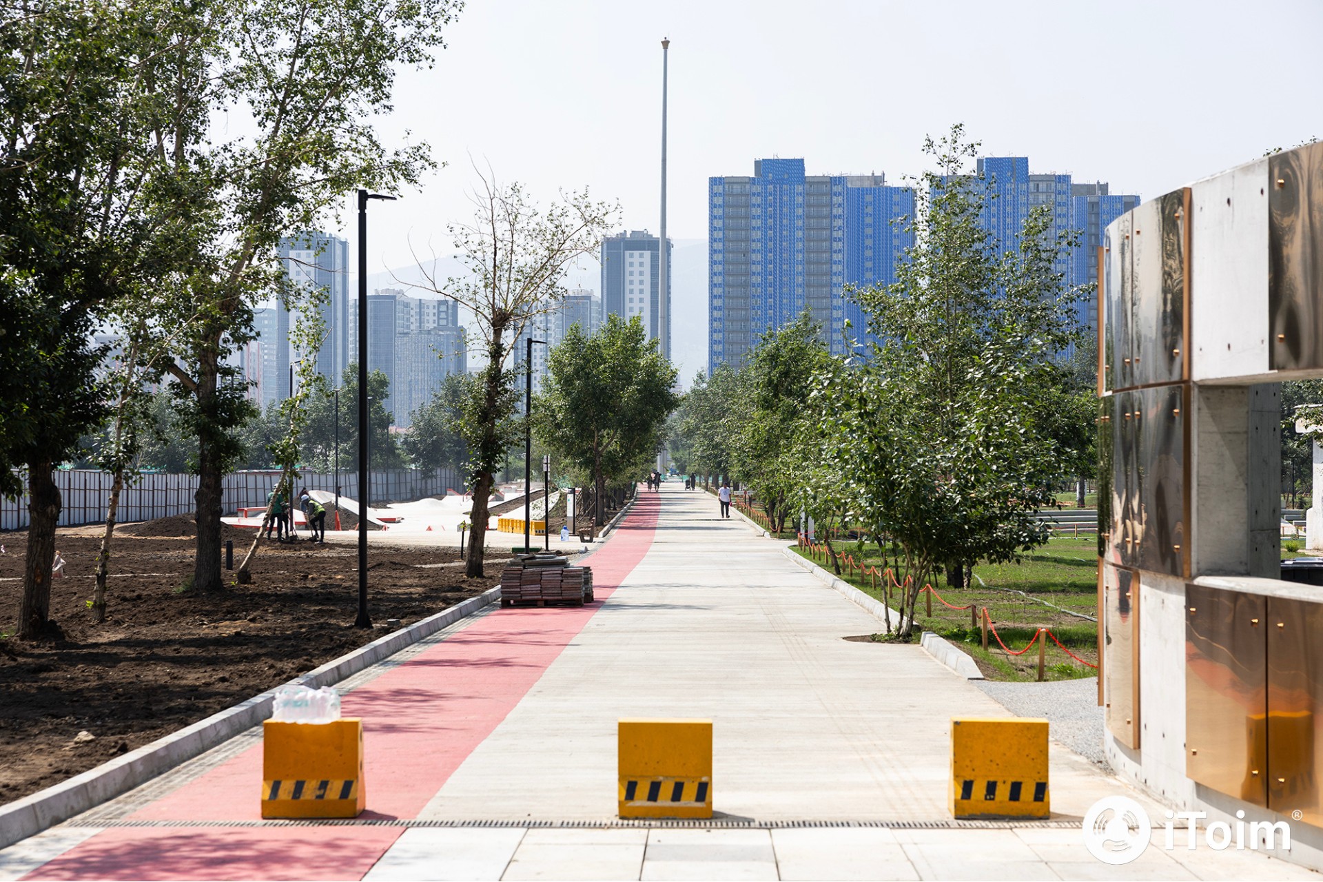 Pedestrian walkway at National Cultural Recreation Park in Ulaanbaatar with trees, urban skyline, and open public space