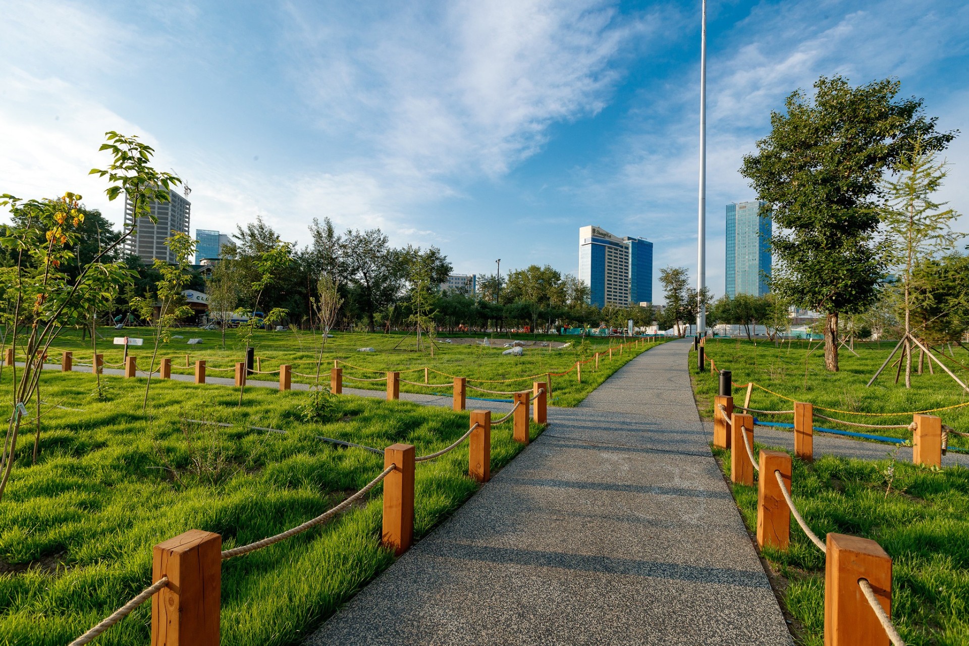 Green park pathway at National Cultural Recreation Park in Ulaanbaatar with landscaped lawns and city buildings in the background