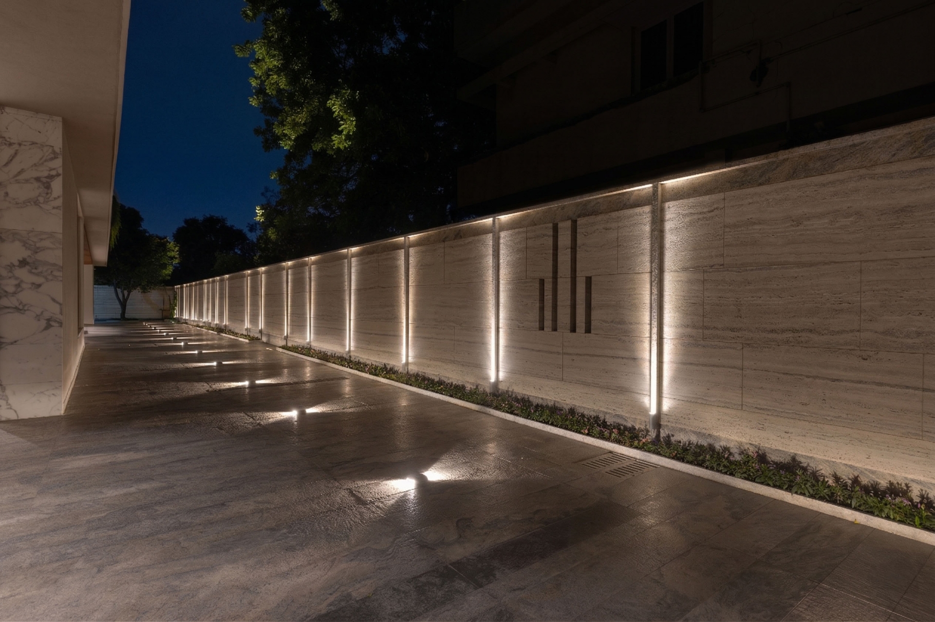 Modern residential driveway lighting with wall and ground luminaires at night